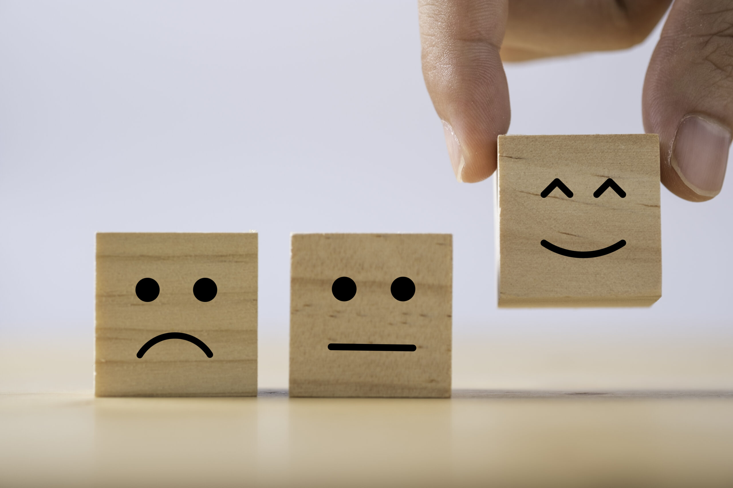 Hand putting smiley emotion to among normal and sad emotion whic